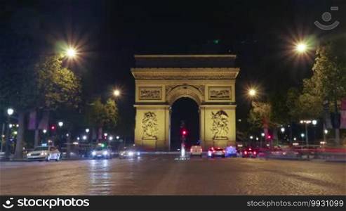 Timelapse low angle shot of cars moving in night street with illuminated Triumphal Arch of the Star. Famous monument in Paris, France