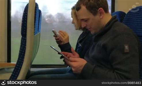 Timelapse of a young man and woman spending time on the train with a tablet PC and smartphone. Comfortable and enjoyable traveling