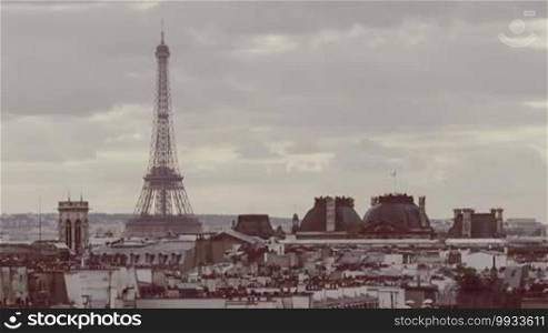 Timelapse of clouds sailing over Paris, view to the city and Eiffel Tower with working elevators. Retro color toned shot with the capital symbol