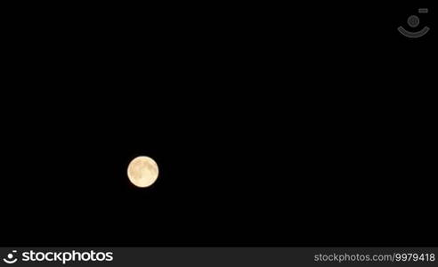 Timelapse of full moon moving against black night sky