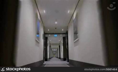 Timelapse steadicam and low angle shot of moving through the modern and light hotel corridor to the doorway