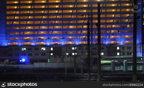 Train passing by the lighted building in the city at night