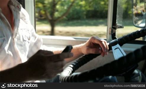 Truck Driver Using Mobile Phone in Cab of Delivery Truck