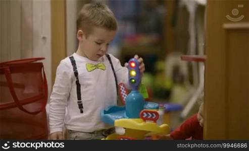 Two cute young preschool children playing with their toys with a toy traffic light and colorful plastic accessories
