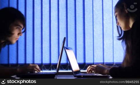 Two people typing on a laptop