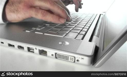 Typing fingers on a silver laptop keyboard