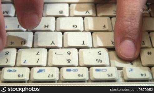 Typing fingers push white notebook keyboard buttons.