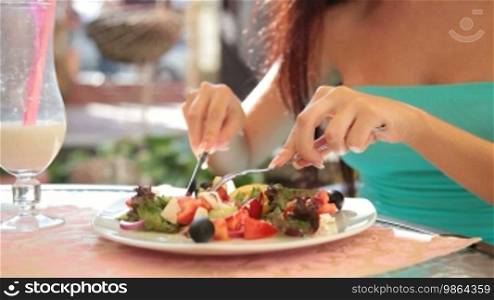Unrecognizable woman eating Greek salad at a restaurant
