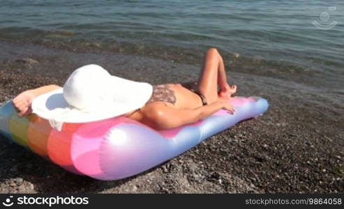 Unrecognizable young woman sunbathing, lying on a pool raft by the sea