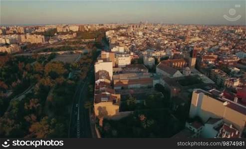 Valencia aerial view with dense house development and green parks in warm light of sunset, Spain