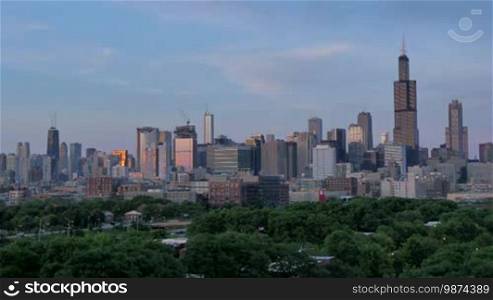 Video timelapse of Chicago downtown skyscrapers from the west of the city center financial district. Awesome Chicago city center skyline at night in the United States of America. Illuminated skyscrapers of Chicago in Spring twilight. Chicago sky in the evening with the sun on the city sky.