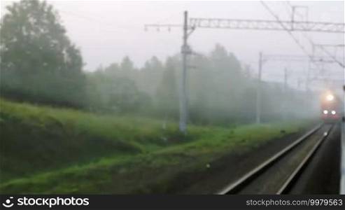 View from moving train of an oncoming train with all carriages passing by