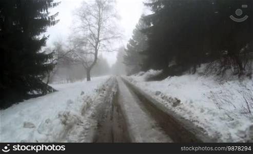 View of an empty road in the mountains during winter with snow-covered trees on the side