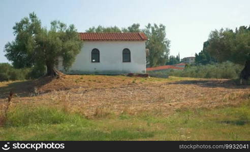 View on building with red roof in countryside on sunny day.