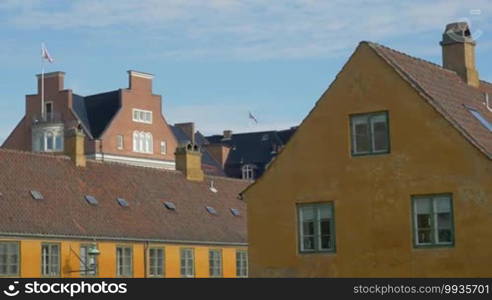 View to the house roofs and worn building in foreground on blue sky background