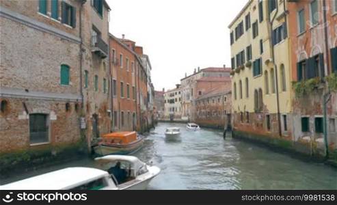 View to the narrow canal in Venice. Motor boats sailing among the old worn houses. Traveling in Europe, Italy