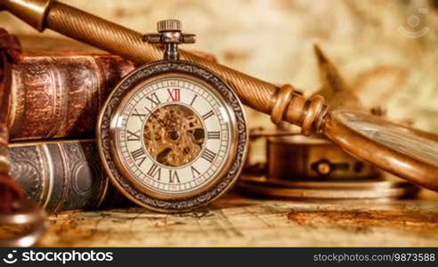 Vintage book, compass, telescope, and a pocket watch lying on an ancient world map in 1565.