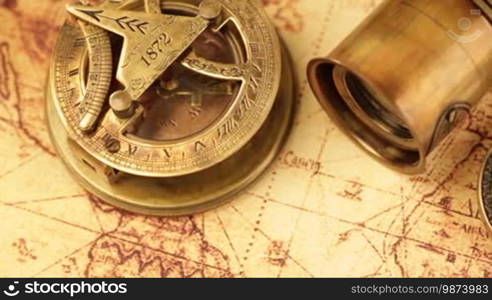 Vintage magnifying glass, compass, telescope, and a pocket watch lying on an ancient world map in 1565.