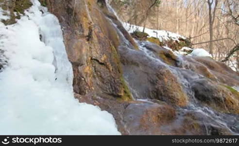 Waterfall, silver stream, and mossy rock in winter. Grand Canyon, Crimea, Ukraine