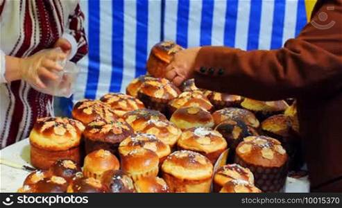 Woman chooses and buys paska (Easter bread in Ukraine) on Ukrainian fair