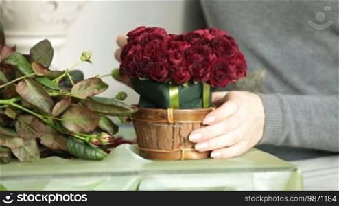 Woman Florist Creating Red Roses Bouquet Arranged in Heart Shape in Flower Shop Closeup