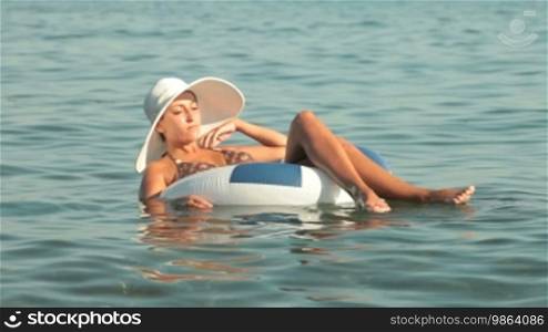 Woman in a white hat floating on the innertube