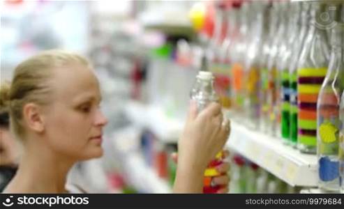 Woman in the shop choosing decorative bottle. Interior objects