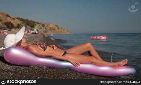 Woman in white sun hat sunbathing on beach