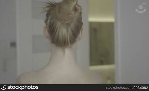 Woman putting hair in ponytail before shower