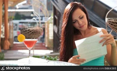 Woman reading a letter while sitting at a table in a cafe