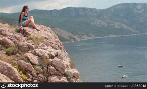 Woman sitting on the edge of a cliff in Balaklava, Crimea, Ukraine