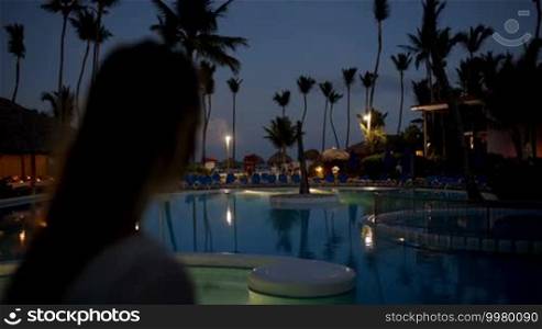 Woman using tablet computer to take photos on tropical resort in the evening