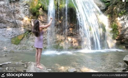 Woman with outstretched arms, standing at the waterfall Jur-Jur, Crimea