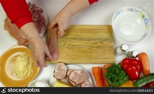 Women's hands are preparing rolls of chicken breast, add bacon and cheese. High speed shot.