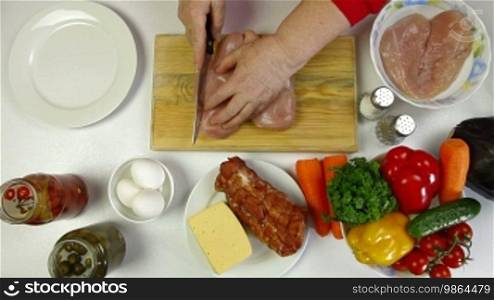 Women's hands cutting chicken breast. Shot from above
