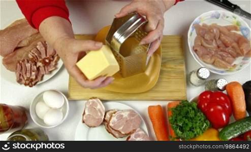 Women's hands grating cheese, an ingredient for cooking chicken roll. Shoot from above