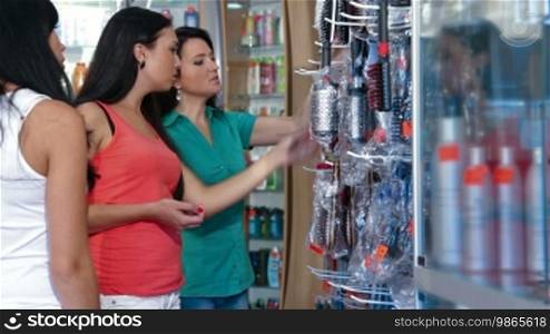 Women shopping in cosmetics store, choosing hairbrush