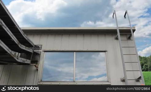 Worker climbs up metal ladder to house and goes out on roof