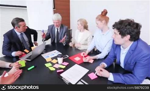 Working process at a business meeting, people sitting around an office table discussing ideas