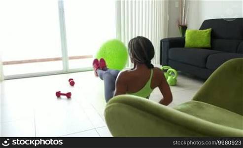 Young adult African American woman in sports clothing at home, doing domestic fitness and training abdominals on pad