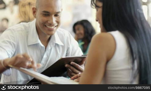 Young adult Hispanic couple dining out in restaurant and reading menu. Dolly shot