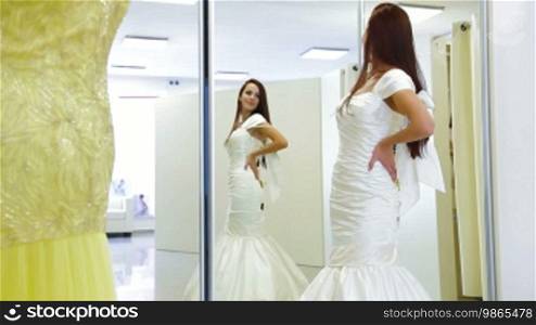 Young attractive bride trying on wedding gown in bridal shop