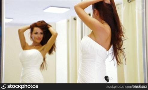 Young attractive woman choosing wedding dress in bridal boutique