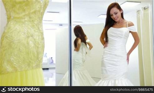 Young attractive woman choosing wedding shoes in bridal shop, posing and looking at camera