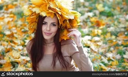 Young attractive woman enjoying autumn day in the park, looking at camera, medium shot