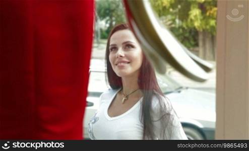 Young attractive woman looking excitedly into the window of a shop
