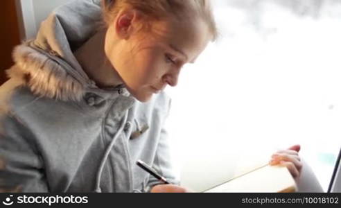 Young beautiful girl writing in her journal and daydreaming.