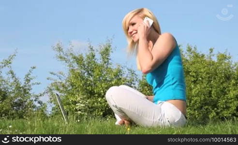 Young blonde woman outside speaking on the phone