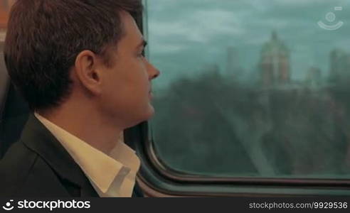 Young businessman is traveling by train and checking time on his wristwatch in wait for arrival.