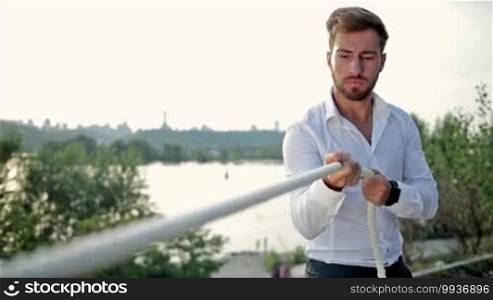 Young businessman pulling hard a rope. Tug of war concept